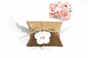 Detail of kraft paper pillow gift box with twine and baby illustration flower tag