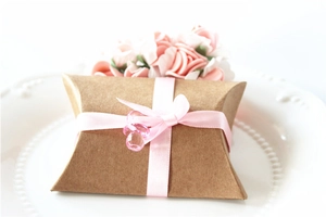 Detail view of brown kraft paper pillow box with pink satin ribbon and crystal pendant