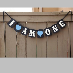 I AM ONE black paper banner with white letters and blue hearts for first birthday party