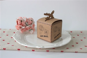 Detail of air mail themed kraft paper gift box with airplane shaped closure on a plate
