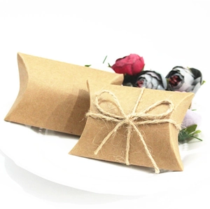 Pillow-shaped kraft paper wedding favor boxes with twine bow and floral background