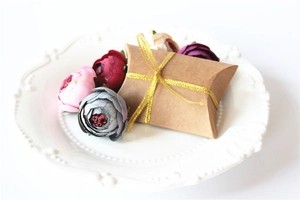 Detail of kraft paper pillow gift box with golden ribbon and decorative flowers