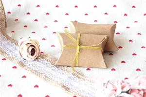 Detail of kraft paper pillow candy boxes with golden ribbon for wedding favors