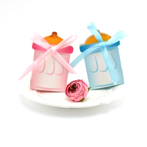 Vue détaillée de boîtes à bonbons biberons avec nœuds en satin sur une assiette blanche