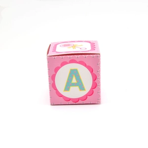 Front view of pink square baby shower gift box featuring letter A and rattle design