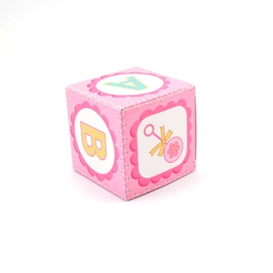 Close-up of pink square candy box featuring yellow baby letters and rattle illustrations