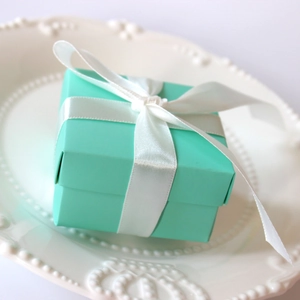 Elegant tiffany blue square wedding favor box with a white satin ribbon bow on a ceramic plate
