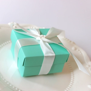 Detail of Tiffany blue wedding favor box featuring a white satin ribbon bow on ceramic plate