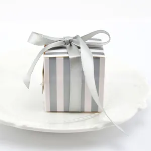 Detail of square gray striped gift box with a silver satin ribbon on a ceramic plate