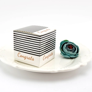 Square black and white striped gift box with gold Congrats lettering on a white plate