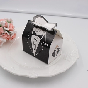 Detailed close-up of tuxedo-style wedding favor box with a bow tie on a decorative plate