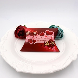 Detail of red pillow candy box with heart patterns on a white embossed ceramic plate