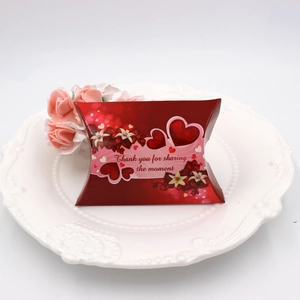 Detail of red pillow candy box with floral patterns on white plate with roses