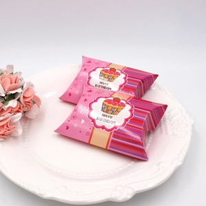 Detalle de cajas de regalo rosas tipo almohada con estampado de cupcake en plato