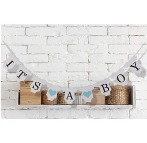 Striscione It's a Boy con carte a forma di body e cuori blu su muro di mattoni bianchi
