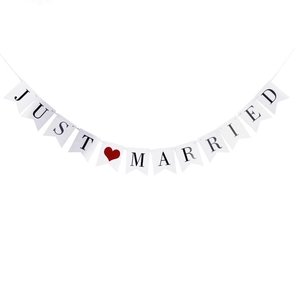 Détail de la banderole de mariage JUST MARRIED blanche avec lettres noires et cœur rouge