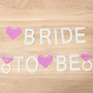 Close-up of silver glitter Bride To Be banner with pink hearts and diamond ring icons