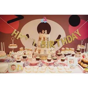 Nahaufnahme einer goldenen Happy Birthday Girlande auf einem rosa Party-Desserttisch