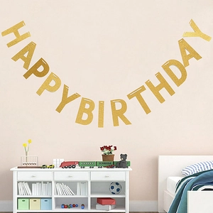 Detailaufnahme der goldenen Happy Birthday Girlande an einer Wand im Kinderzimmer
