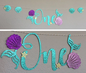 Detail of mermaid themed first birthday banner with glitter sea shells and starfish