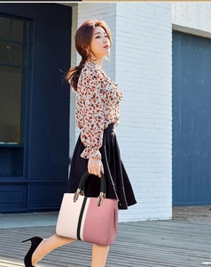 Outdoor shot of stylish color-block tote bag with pink and white panels and black round handle