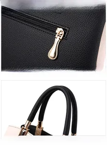 Close-up of color-block handbag showing golden zipper and soft leather handle details