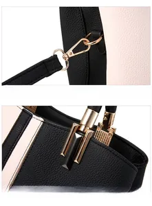 Detail of glossy gold metal buckle and stylish black charm on color-block handbag