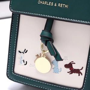 Detail of green and beige leather bag featuring cartoon dog embroidery and golden logo