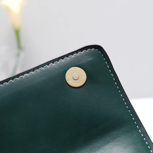 Detail shot of green textured leather bag with premium gold magnetic snap closure
