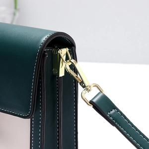 Detail shot of green and white leather stitching with premium gold hardware hooks