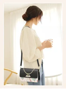 Détail du sac bandoulière avec motif Tour Eiffel et pendentif cygne perlé élégant