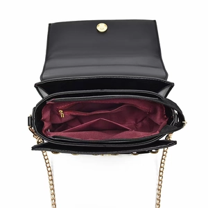 Intérieur du sac en cuir noir montrant la doublure bordeaux et le fermoir doré