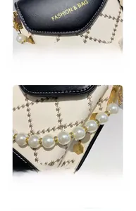 Détail montrant le logo doré et l'élégante chaîne de perles sur le sac à main