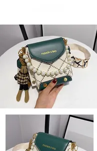 Détail du sac bandoulière vert et blanc avec poignée en perles et breloque lapin