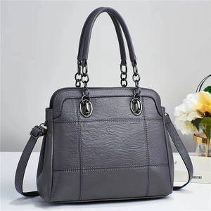 Close-up of grey leather tote bag featuring quilted pattern and metal chain handle
