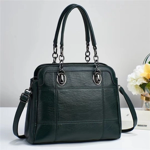 Dark green quilted leather tote bag with metal chain handles and detachable strap