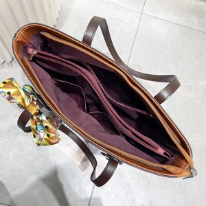 Interior view of brown faux leather tote bag with purple lining and multiple pockets
