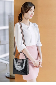Detail of black crocodile texture bucket bag with colorful striped fabric shoulder strap