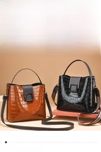 Detail view of glossy crocodile pattern bucket bags with red and green striped straps
