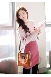 Brown crocodile embossed patent leather bucket bag shown on a model in a bright room