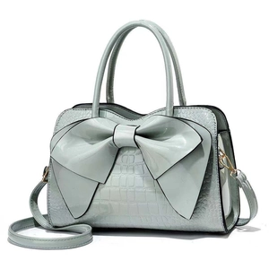 Light green crocodile pattern handbag with large bow decoration and gold shoulder strap