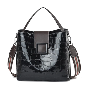 Glossy black patent leather bucket bag with crocodile texture and striped strap