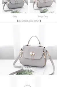 Detail view of light gray faux leather handbag with pearl cat charm and metal zipper