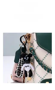 Detail of creative cartoon bear pendant with checkerboard strap on a stylish handbag