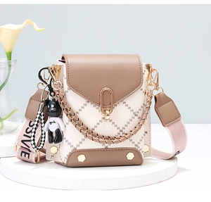 Close-up of a quilted mini crossbody bag featuring a golden buckle and bear charm detail