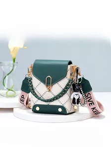 Detail of green and beige crossbody bag with quilted embroidery and cute bear charm