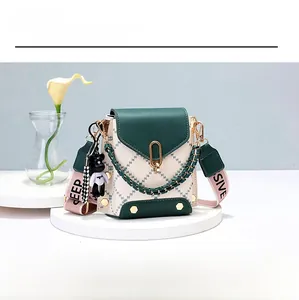 Close-up of green and white quilted crossbody bag with gold chain and bear charm
