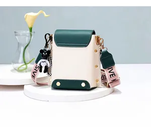 Rear view of mini crossbody bag in green and beige with MISSIVE strap and bear charm
