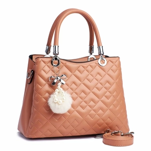 Detail of nude pink quilted leather handbag with pearl bow pompom and adjustable strap
