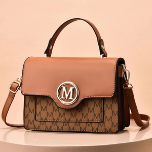 Detail of a brown leather handbag with M monogram pattern and round metal logo buckle